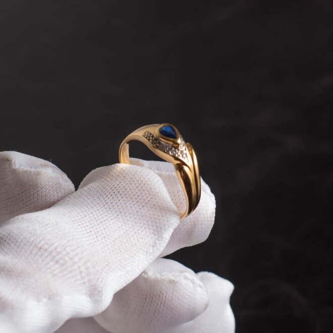 Anillo de Oro 18k con zafiro azul central y engarces de diamantes