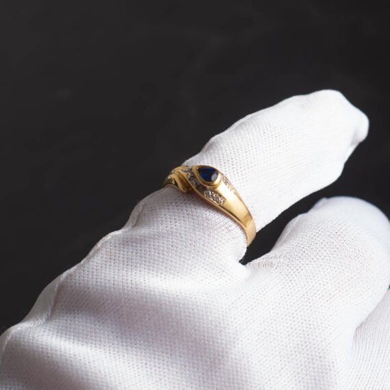 Anillo de Oro 18k con zafiro azul central y engarces de diamantes